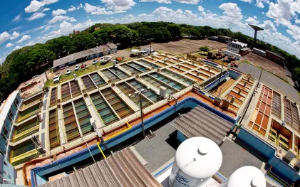 Estrutura de concreto de uma estação de tratamento de água com calhas e divisórias inundadas por água em processo de filtragem e decantação.