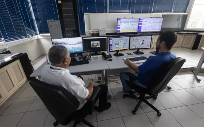 tecnicos no centro de controle operacional observando as telas dos computadores
