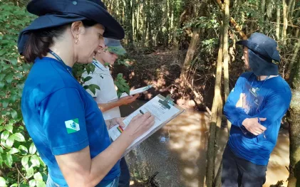 Empregados com pranchetas analisam condição do rio