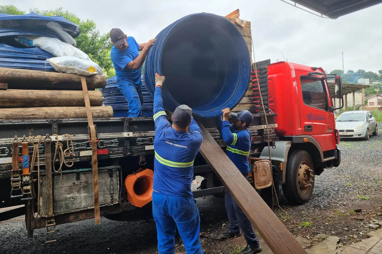 três homens descarregando caixas d'água de um caminhão estacionado