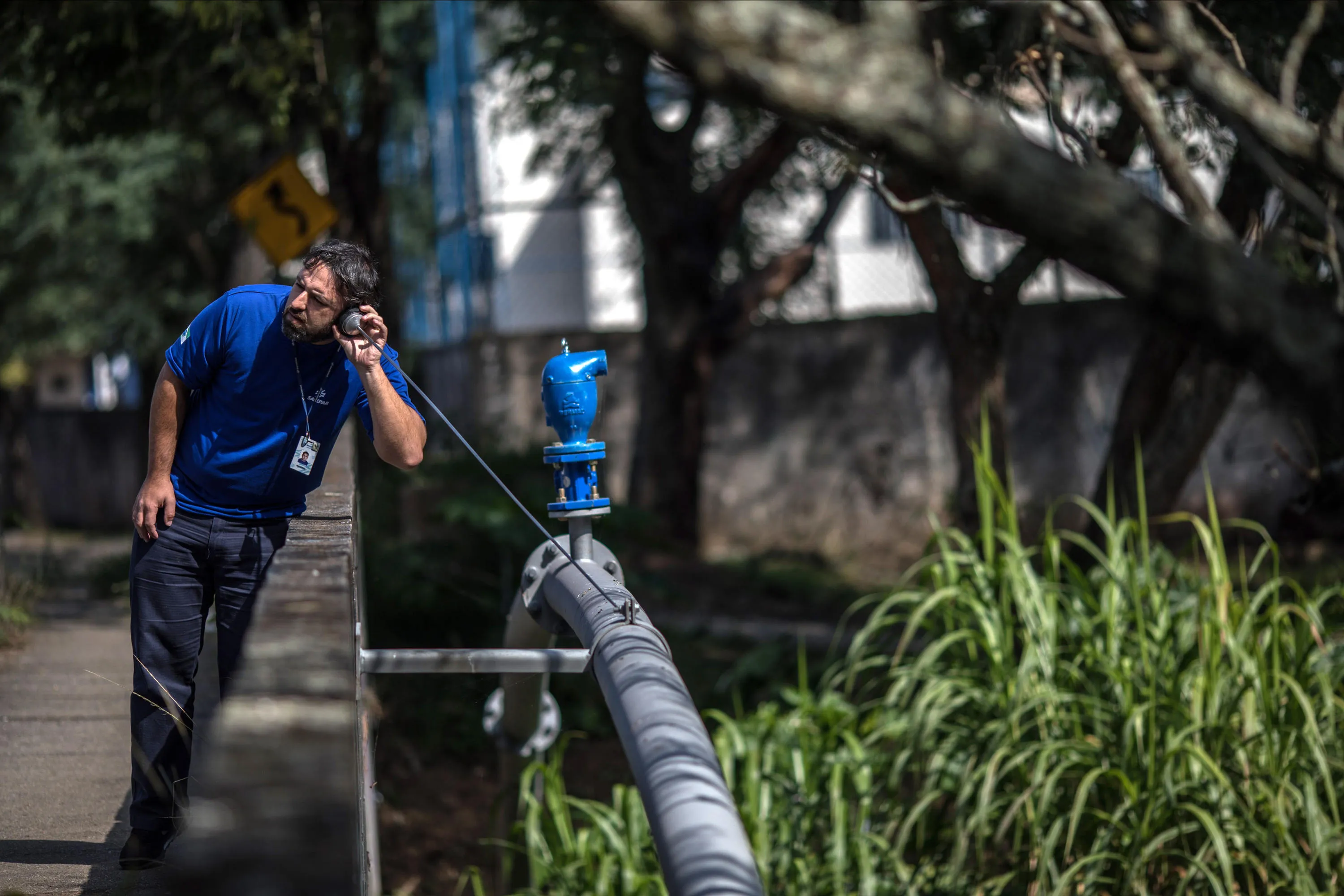 Homem com escuta no ouvido próximo à uma tubulação de água